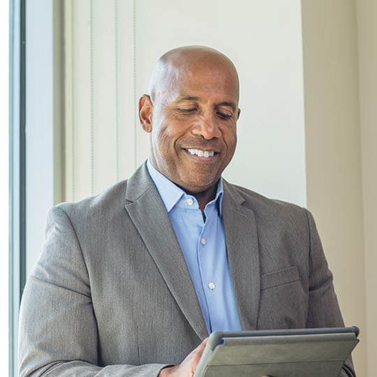 Image of older man smiling while on a tablet.