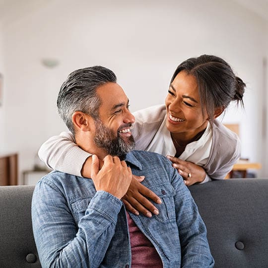 Image of younger couple laughing and embracing.