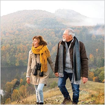 Image of older couple hiking with mountains in background.