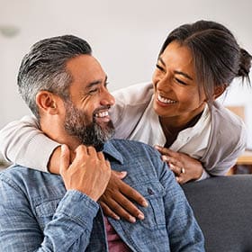 Image of younger couple laughing and embracing.
