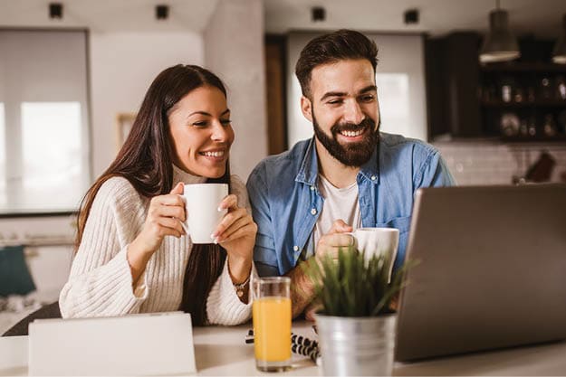 Happy couple enjoying work from home. Happy couple doing business together working at home on the laptop.