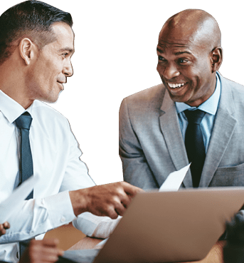 Diverse group of smiling businesspeople going over paperwork together and working on a laptop at a table in an office