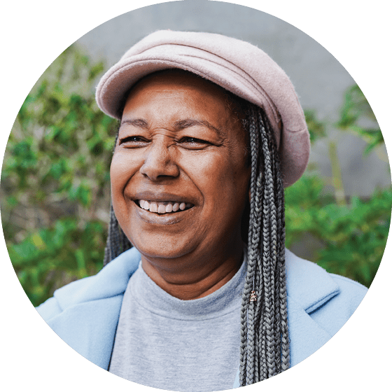 Portrait of happy senior african woman wearing trendy hat and smiling in front of camera during winter time