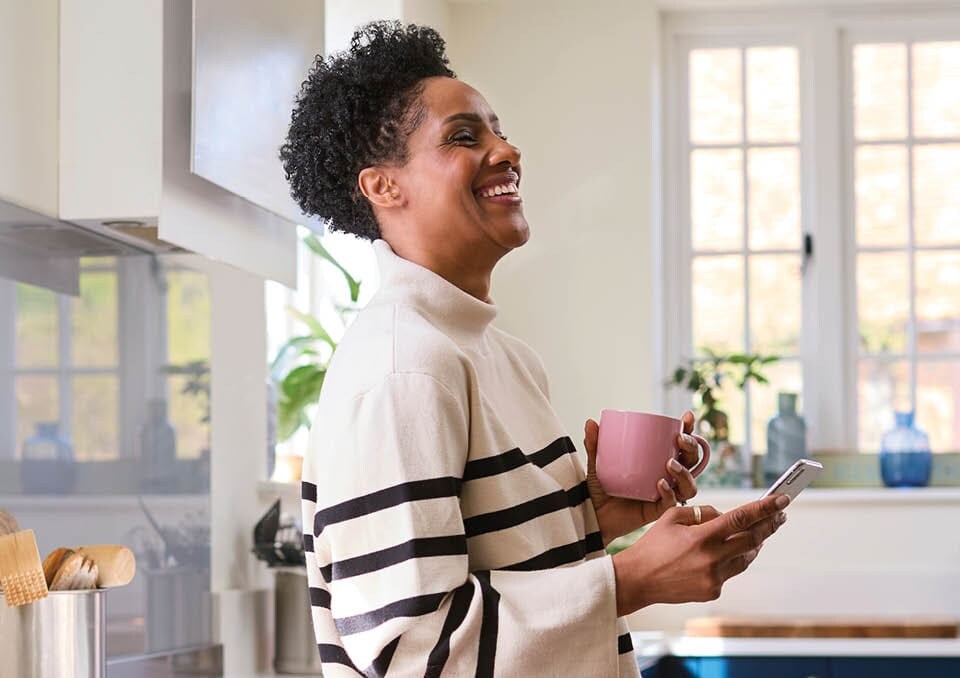 woman holding smart phone in her kitchen