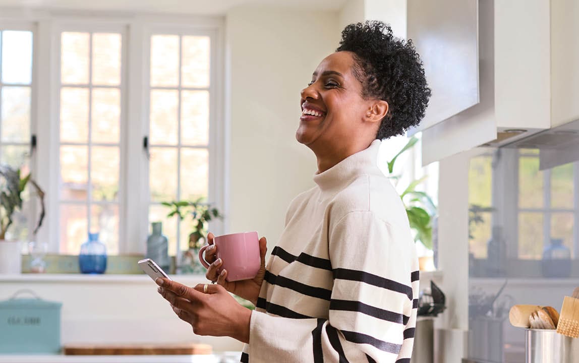 woman holding smart phone in her kitchen