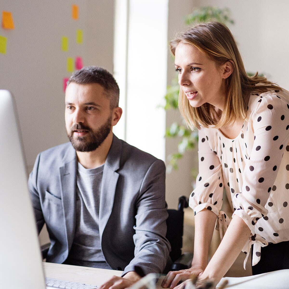 A businessman and businesswoman are looking at a computer screen together