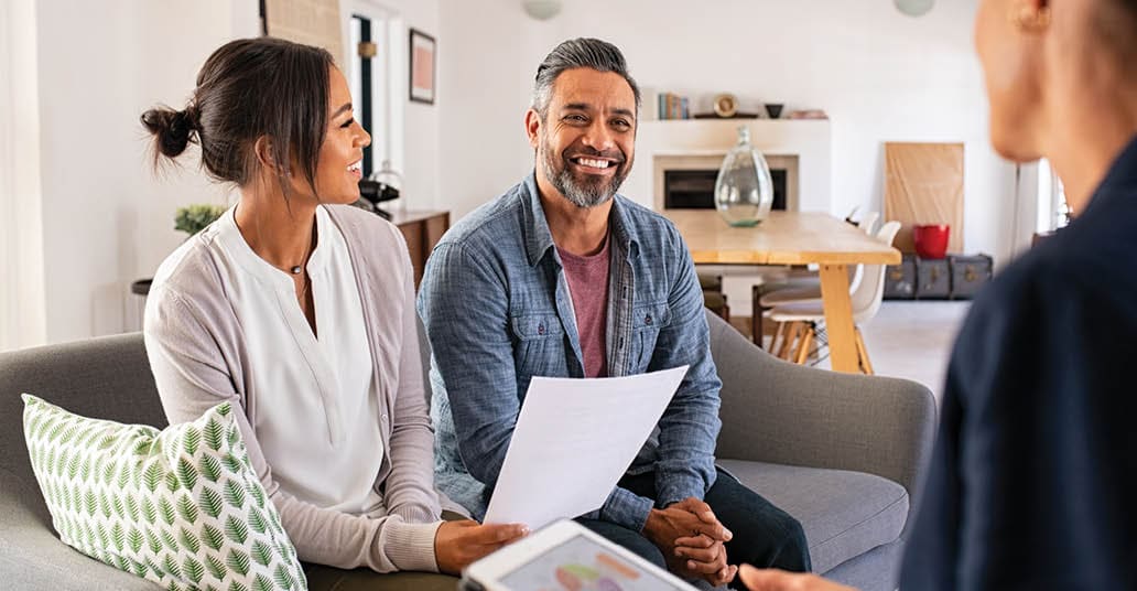 Happy mature couple discussing investments with financial broker during meeting at home. Happy middle eastern man and hispanic woman discussing about financial planning with consultant at home. Financial consultant presenting new investment plan to smiling mature couple at home.