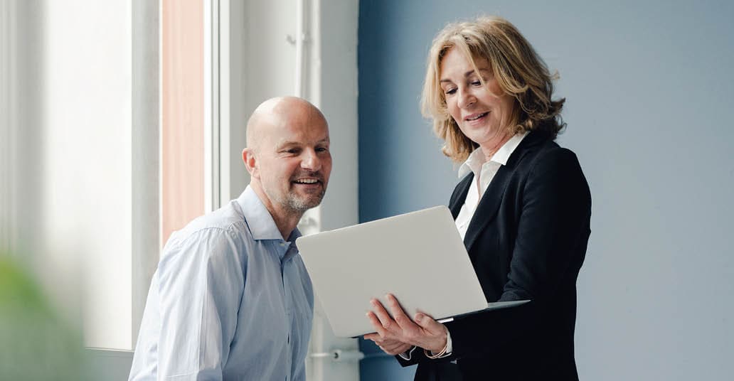 two colleagues looking a laptop together