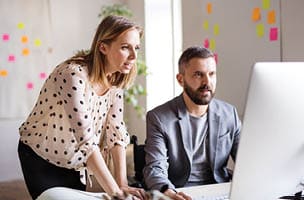 colleagues looking at a desktop computer screen