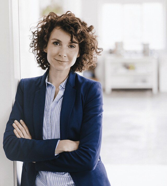 businesswoman leaning against wall with arm crossed