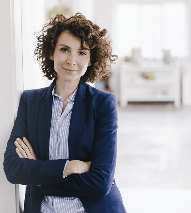 businesswoman leaning against wall with arm crossed