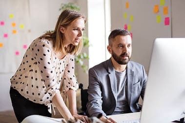 colleagues looking at a desktop computer screen